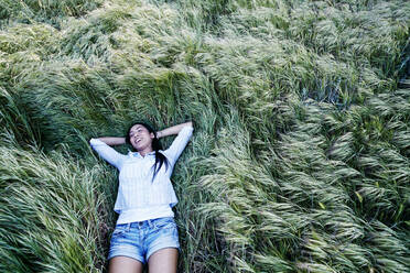 Mixed race woman laying in grass - BLEF11669