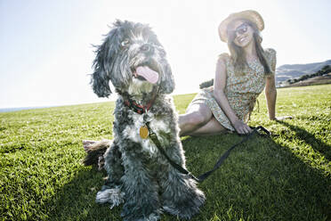 Caucasian woman sitting in field with dog - BLEF11698