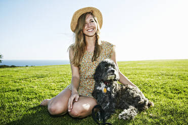 Caucasian woman sitting in field with dog - BLEF11699