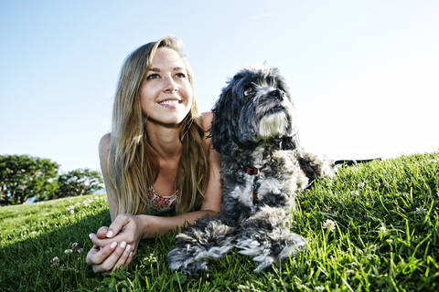 Caucasian woman sitting in field with dog stock photo