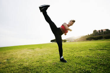 Black woman kick boxing in field - BLEF11763