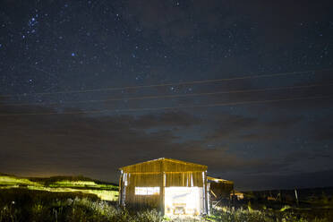 Illuminated cabin under starry night sky - BLEF11792