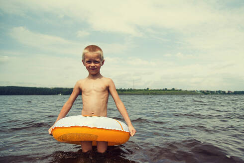 Kaukasischer Junge spielt im Schlauchboot im See - BLEF11846