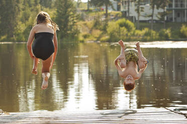 Caucasian children jumping into lake - BLEF11853
