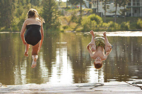Kaukasische Kinder springen in den See - BLEF11853