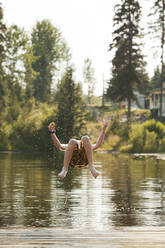 Caucasian boy jumping into lake - BLEF11854