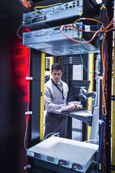 Hispanic technician using computer in server room - BLEF11875