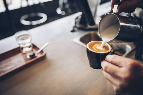 Kaukasischer Barista schenkt Kaffee in einem Café ein - BLEF11909