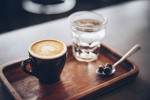 Tablett mit Kaffee, Kaffeebohnen und Wasser im Cafe - BLEF11910