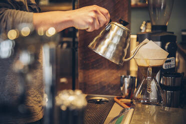 Kaukasischer Barista gießt heißes Wasser über Kaffee in einem Café - BLEF11911