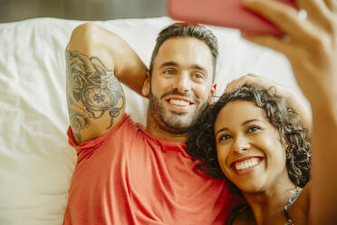 Couple taking selfie with cell phone on bed - BLEF11919