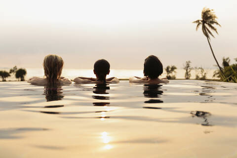 Frauen bewundern die malerische Aussicht im Infinity-Pool, lizenzfreies Stockfoto