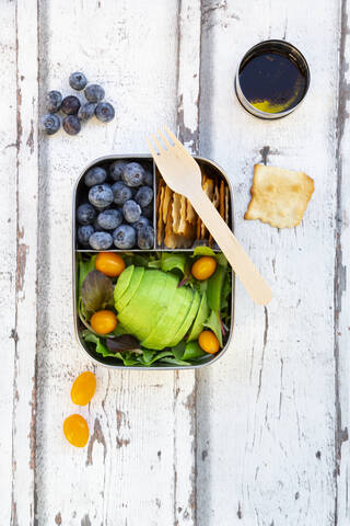 lunchbox/prep meal (gemischter grüner Salat mit Avocado und gelben Tomaten, Cracker, Blaubeeren, Salatsauce), Holzgabel, (alles ohne Platik), lizenzfreies Stockfoto