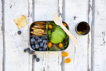 Lunchbox with salad, avocado and yellow tomatoes, crackers, blueberries and salad dressing - LVF08195