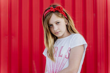 Porträt eines Mädchens mit Haarband vor einer roten Wand - ERRF01611