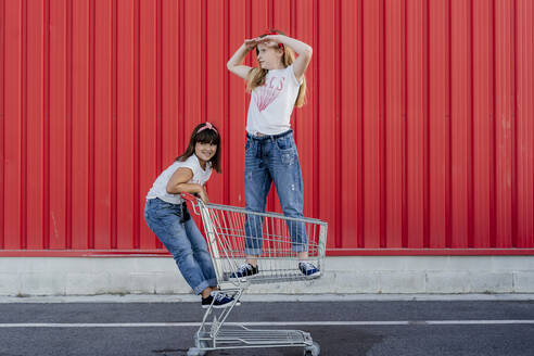 Schwestern mit Einkaufswagen vor einer roten Wand - ERRF01638
