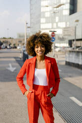 Portrait of smiling young woman wearing fashionable red pantsuit - GIOF06852