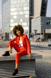 Portrait of smiling young woman wearing fashionable red pantsuit - GIOF06856