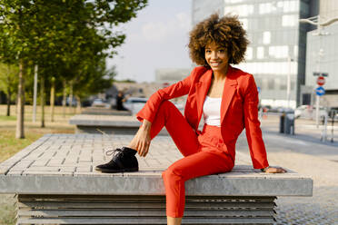 Portrait of smiling young woman wearing fashionable red pantsuit - GIOF06857