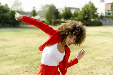Porträt einer sich bewegenden jungen Frau in modischem roten Hosenanzug und weißem Oberteil - GIOF06860