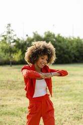 Portrait of laughing young woman wearing fashionable red pantsuit - GIOF06861