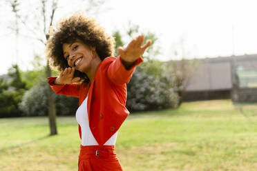 Portrait of laughing young woman wearing fashionable red pantsuit - GIOF06862