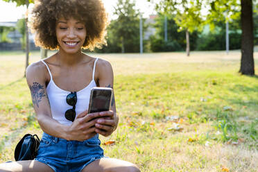 Porträt einer tätowierten jungen Frau, die im Sommer ein Selfie mit ihrem Smartphone macht - GIOF06907