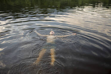 Junge schwimmt abends in einem See - VPIF01382