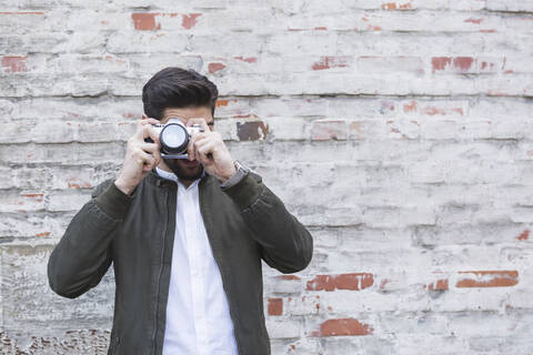 Junger Mann beim Fotografieren mit Kamera, lizenzfreies Stockfoto