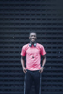 Porträt eines lachenden Mannes mit Kopfhörern und rosa T-Shirt - OCMF00519