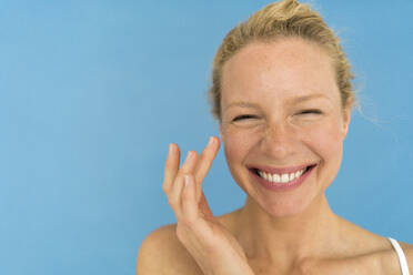 Portrait of beautiful blond woman applying eye cream - JOSF03539