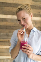 Smiling blond woman drinking a smoothie - JOSF03557