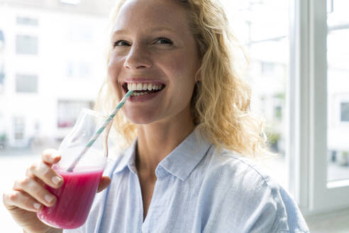 Smiling blond woman drinking a smoothie - JOSF03558