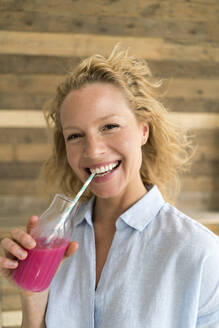 Lächelnde blonde Frau trinkt einen Smoothie - JOSF03559