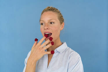 Portrait of blond woman with raspberries on his fingers - JOSF03562