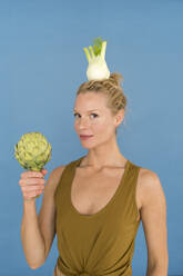 Smiling blond woman with fennel, blue background - JOSF03566