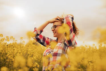 Smiling young woman in a rape field, hand in hair - SEBF00111