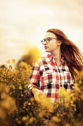 Young woman in a rape field looking sideways - SEBF00112