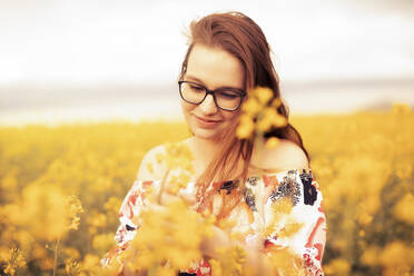 Smiling young woman in a rape field - SEBF00115