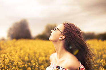 Smiling young woman in a rape field - SEBF00116