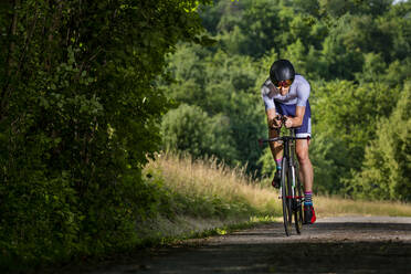 Triathlet fährt Fahrrad auf Landstraße, Deutschland - STSF02137