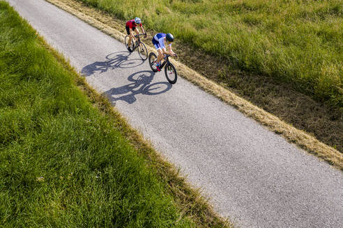 Triathleten fahren mit dem Fahrrad auf einer Landstraße, Deutschland - STSF02142