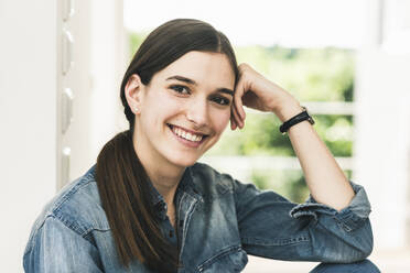 Portrait of smiling young woman wearing denim shirt at home - UUF18262