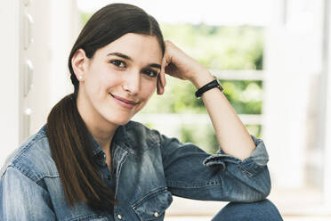 Portrait of smiling young woman wearing denim shirt at home - UUF18263