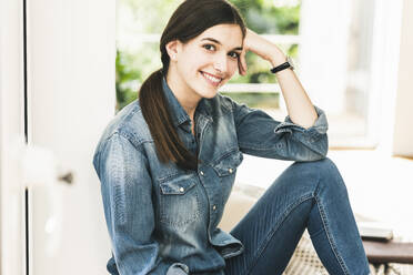 Portrait of smiling young woman wearing denim shirt at home - UUF18264