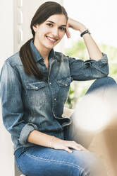Portrait of smiling young woman wearing denim shirt at home - UUF18265