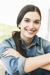 Portrait of smiling young woman wearing denim shirt at home - UUF18266