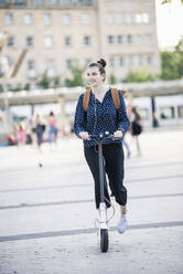 Young woman riding electric scooter in the city - UUF18286