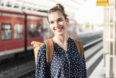 Porträt einer lächelnden jungen Frau auf dem Bahnhof - UUF18297