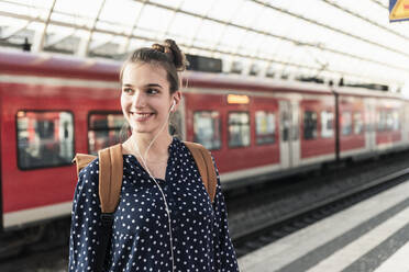 Porträt einer lächelnden jungen Frau auf dem Bahnhof - UUF18299